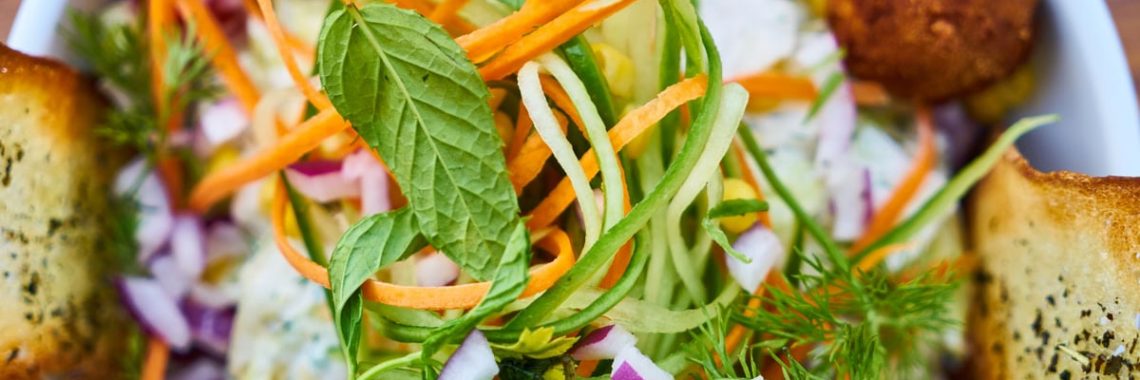 Vibrant salad featuring fresh vegetables, falafel, and herbs in a white bowl, perfect for a healthy meal.
