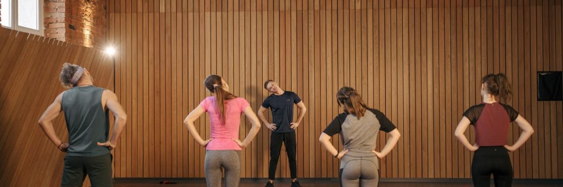 Men and women performing stretching exercises on mats in a fitness class