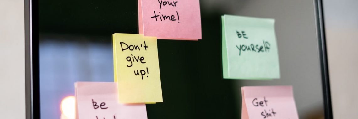 Colorful sticky notes with motivational messages on a mirror reflecting positivity.
